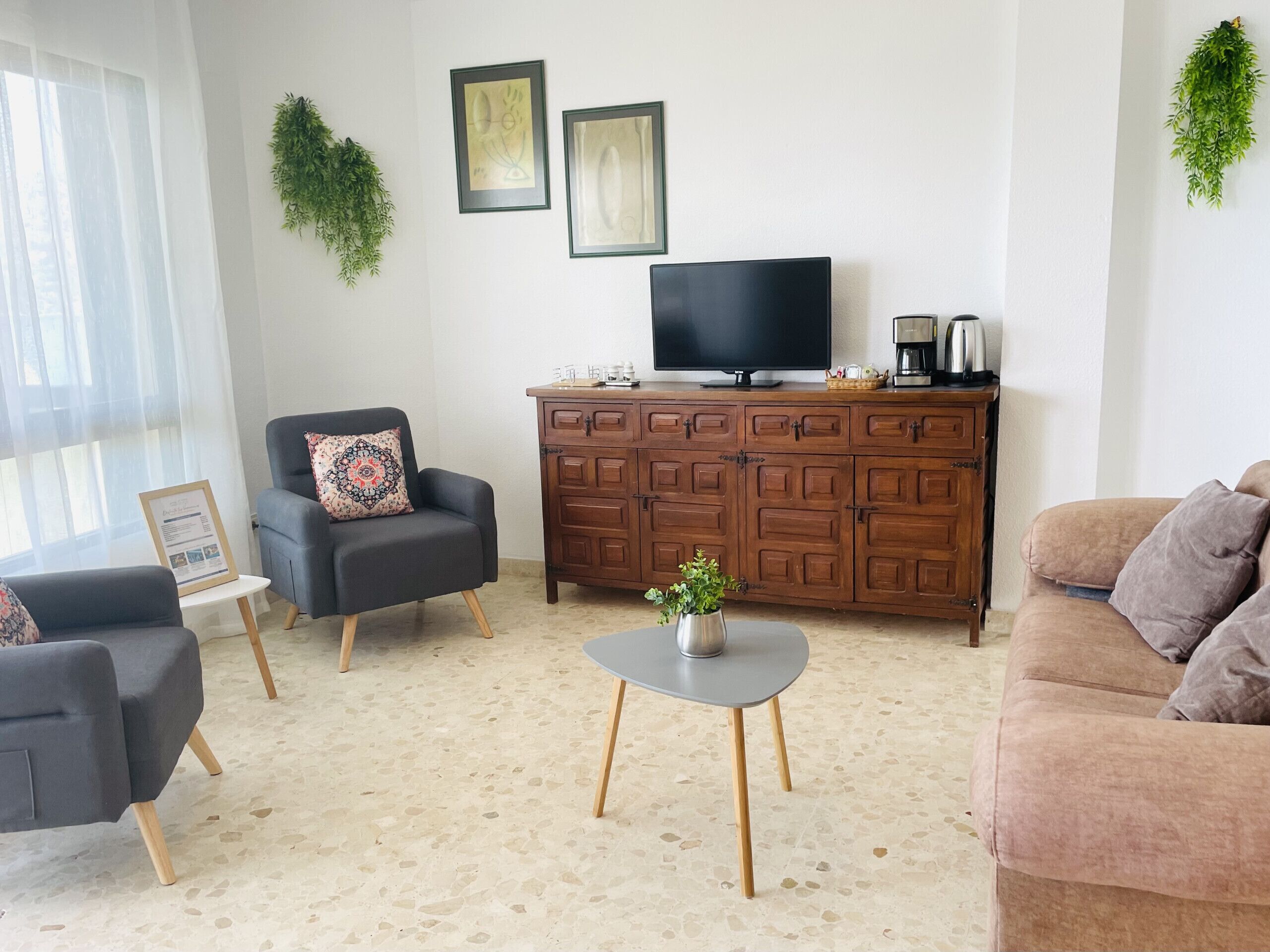 A living room with a sofa, armchair, coffee table, and a TV on a wooden cabinet.