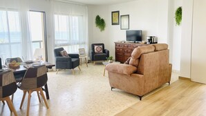 Un salon moderne comprenant un canapé, des fauteuils, une table à manger et un téléviseur.