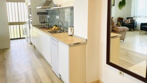 Une cuisine moderne avec des meubles blancs, un évier en acier inoxydable et un dosseret carrelé.