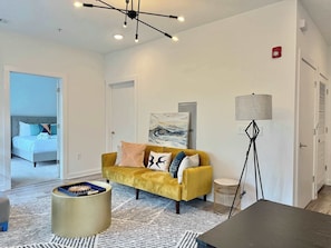A modern living room with a sofa, a lamp, a coffee table, and a painting on the wall. - Modern Condo in Old Fourth Ward (Atlanta)
