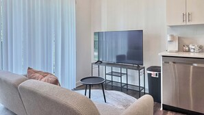 Un salon moderne avec un téléviseur à écran plat, une petite table ronde et un canapé.