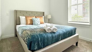 Une chambre à coucher avec un lit, une table de chevet, une lampe et une fenêtre avec des stores.