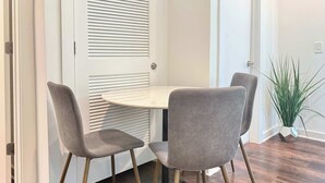 Un coin repas avec une table ronde et quatre chaises grises aux pieds en bois.