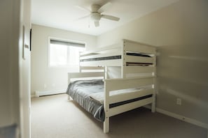 A bunk bed in a room with a ceiling fan, a window, and a radiator. - Park Point Oasis | On Lake Superior | Duluth (Duluth)