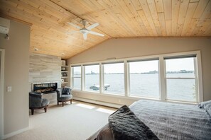 A bedroom with a large window, a ceiling fan, and a fireplace. - Park Point Oasis | On Lake Superior | Duluth (Duluth)
