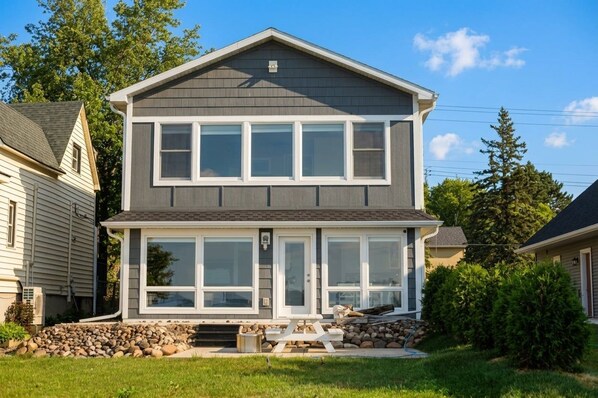 A two-story house with a front porch, a stone foundation, and a clear sky. - Park Point Oasis | On Lake Superior | Duluth (Duluth)
