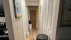 A narrow hallway with a bed on the right, a small table with a bottle, and a painting on the left. - Charming 2-bedroom bed & breakfast with AC, WiFi in awesome Indianapolis (Indianapolis)