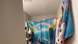 A bathroom with a shower curtain featuring a cartoon character, a toilet, and a small sink. - Charming 2-bedroom bed & breakfast with AC, WiFi in awesome Indianapolis (Indianapolis)