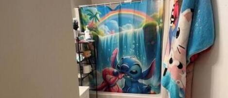 Une salle de bain avec un rideau de douche orné d’un personnage de dessin animé, des toilettes et un petit lavabo.