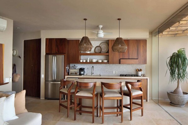 Una cocina moderna con armarios de madera, una isla central e iluminación colgante.