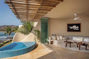 Un espacio exterior moderno con piscina, asientos y vista al océano.