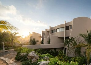 Un edificio moderno con fachada curva, rodeado de vegetación y palmeras.