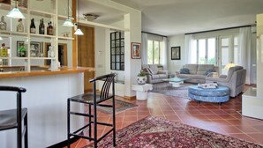 Amplia sala de estar con barra, asientos y vistas al exterior.