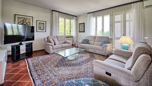 Una sala de estar con dos sofás, una mesa de centro, un televisor y una alfombra estampada.
