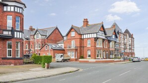 A row of red brick houses with black window frames and a distinctive corner tower. - Hidden Treasure-UK48779 (Whitby)