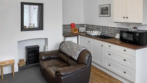 A compact kitchen with white cabinets, a microwave, a toaster, and a fireplace. - Hidden Treasure-UK48779 (Whitby)