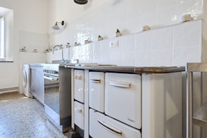 A kitchen with white appliances, a washing machine, and a tiled backsplash. - Room 'Camera 3 - Del Ponti' with Shared Garden and Wi-Fi (Casa Paduletto)