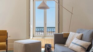 A living room with a sofa, ottoman, and chair, a large window with a view of the sea, and a hanging lamp. - Oceanfront Villa, Near Porto Historical Centre (Porto)
