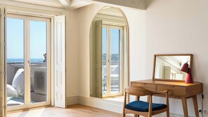 A room with a wooden desk, a chair, and a large mirror. There is a sliding glass door leading to a balcony with a view of the sea. - Oceanfront Villa, Near Porto Historical Centre (Porto)