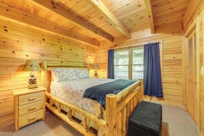 Camera da letto in una casetta di legno, con un letto, un comodino e una panca.