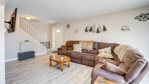 Ein Wohnzimmer mit einem braunen Ledersofa, einem Holztisch und einer Treppe mit einer weißen Geländer.