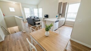 Amplia sala de estar con una mesa de comedor de madera, un sofá y una cocina equipada con electrodomésticos modernos.