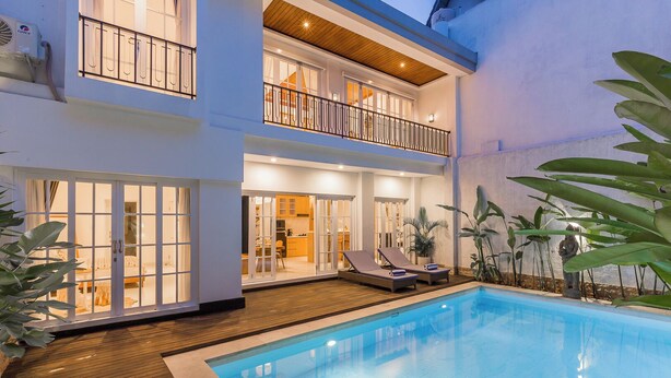 A two-story house with a swimming pool, a balcony with a railing, and a view of the interior.