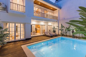 A two-story house with a swimming pool, a balcony with a railing, and a view of the interior. - Villa Namo - Private Luxury 3 BR Villa  (Kerobokan)