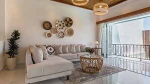 A modern living room with a sectional sofa, decorative wall art, a potted plant, and a glass coffee table.
