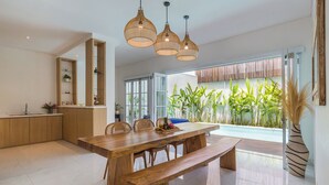 A modern kitchen with a wooden countertop, a dining area with a wooden table and benches, and a view of a swimming pool.
