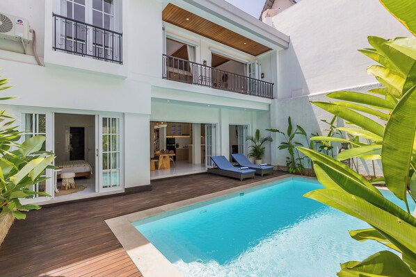 A two-story building with a swimming pool, a balcony, and a dining area.