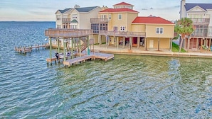 A waterfront property with multiple buildings, a dock, and a pier. - Bayview Home with Boat Slip & Stunning Views (Galveston)