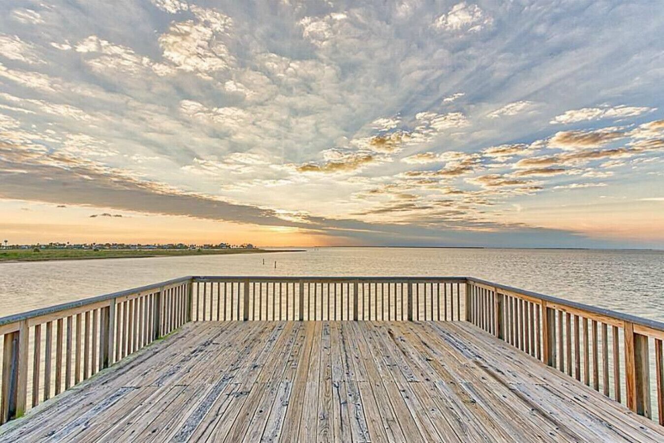 Une terrasse en bois offrant une vue sur l’océan et un magnifique coucher de soleil.
