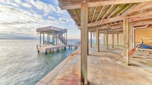 A wooden pier extending into the water with a covered seating area and a staircase leading to a platform. - Bayview Home with Boat Slip & Stunning Views (Galveston)
