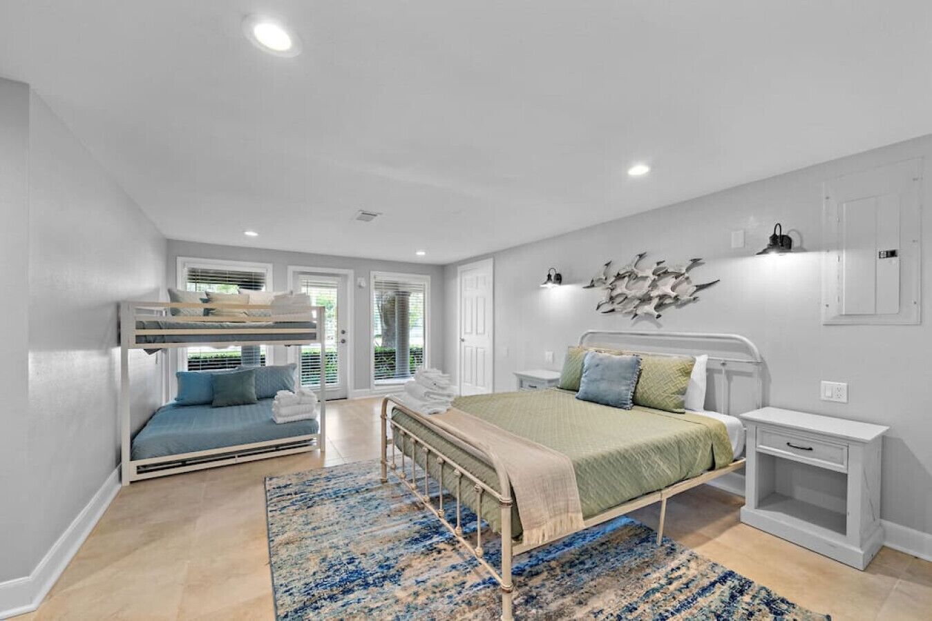 Une chambre à coucher comprenant un lit superposé, un lit simple, une table de chevet et un élément décoratif mural.