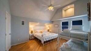 A bedroom with a bunk bed, a ceiling fan, and a window with a starry night view. - Fisherman`s Dream: Game Room & Walk to Beach (Surfside)