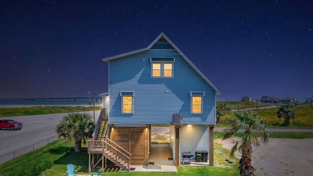 A two-story house with a garage, a covered porch, and a small outdoor seating area with chairs. - Fisherman`s Dream: Game Room & Walk to Beach (Surfside)