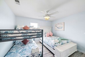 Ein Schlafzimmer mit zwei Etagenbetten, einem Deckenventilator und einer Wand mit dem Schild 'Bay Cruises'.