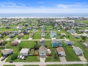 Een woonwijk met huizen, gazons en een strand op de achtergrond.