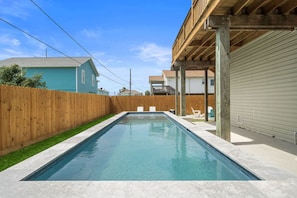 Una piscina rectangular con una cubierta de madera y una barandilla de metal en un lateral.
