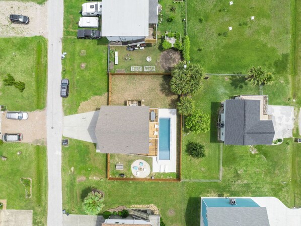 Vista aérea de una propiedad residencial con piscina, garaje independiente y un amplio césped.