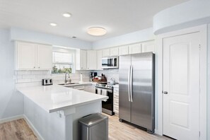 Una cocina moderna con armarios blancos, electrodomésticos de acero inoxidable y una isla grande.