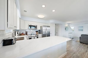 A modern kitchen with white cabinetry, stainless steel appliances, and a large island.