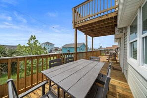 A wooden deck with a table and chairs, overlooking a residential area with houses.