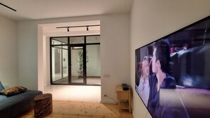 Una sala de estar moderna con un televisor de pantalla plana grande, un sofá azul oscuro y piso de madera.