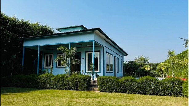 A two-story house with a blue exterior and a covered porch. - Cozy 2-bedroom farmhouse in awesome Noida with AC, WiFi (Noida)