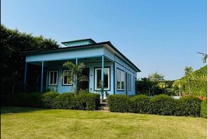 Une maison à deux étages, avec une façade bleue et une véranda.