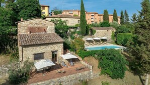 Una villa de piedra con piscina, mobiliario exterior y abundante vegetación.