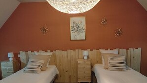 Une chambre avec deux lits, une tête de lit en bois, une table de chevet avec une lampe et un tableau accroché au mur.