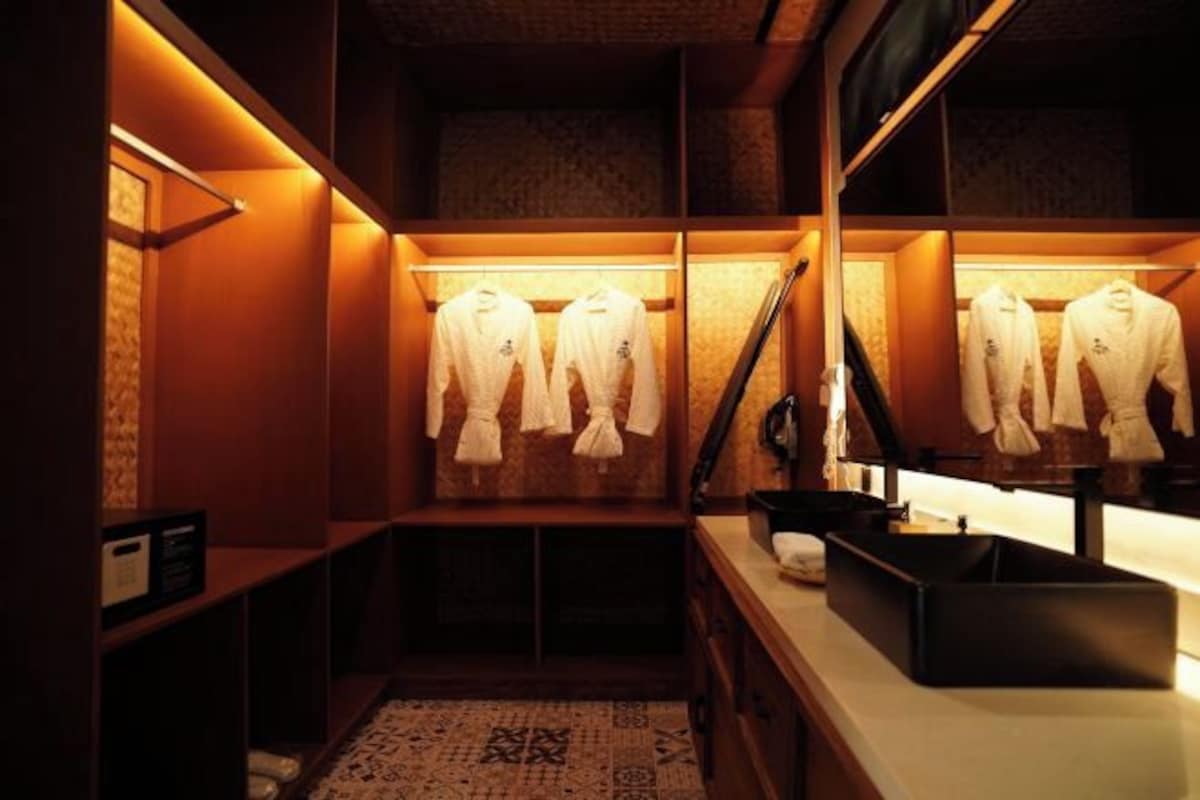 Habitación de hotel con vestidor que contiene batas ordenadas y un cesto negro para almacenaje.